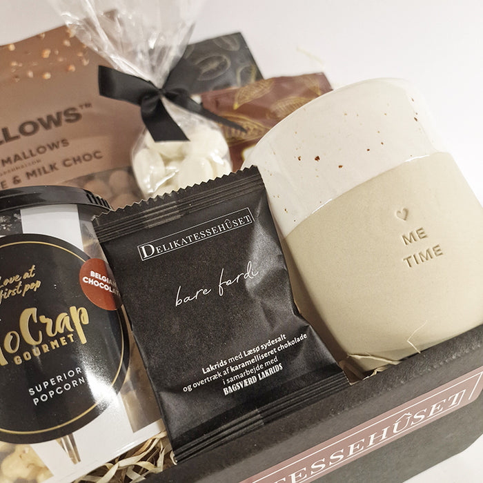 Gavekurv til en hyggestund. Kurven indeholder en unik keramikkop med teksten 'me time', samt kakaopulver og forskellige søde sager.