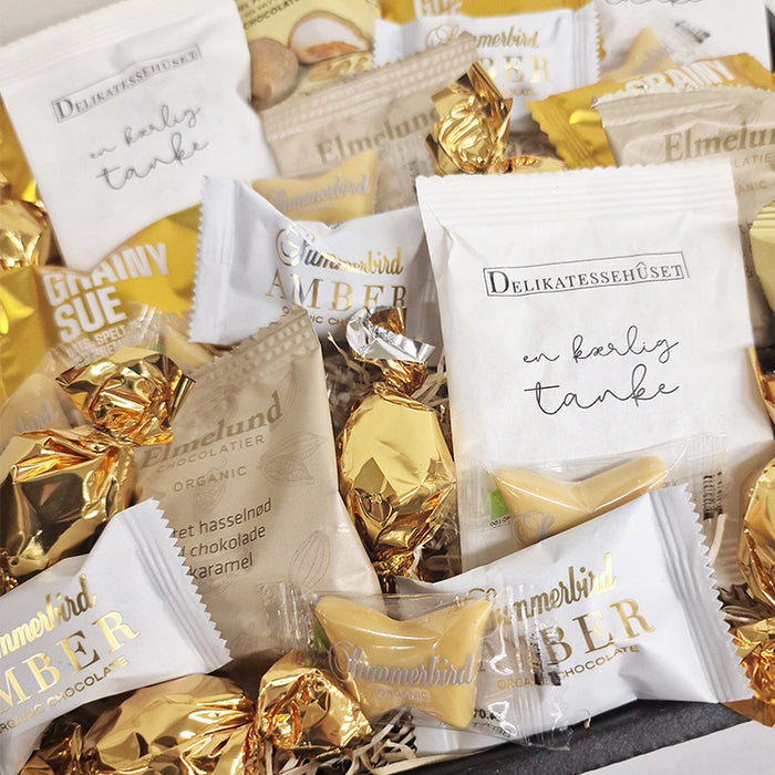 Flowpack kurv med guld lækkerier som chokolade, skumfiduser og lakrids