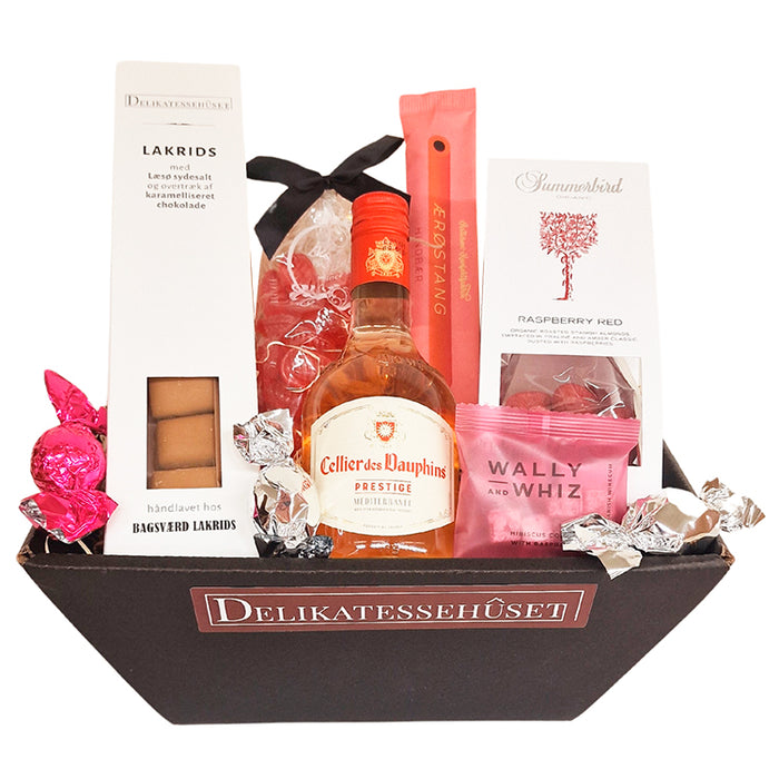 Sød feminin gavekurv med lille flaske fransk rosévin, chokolade, lakrids, mandler vingummi m.m..