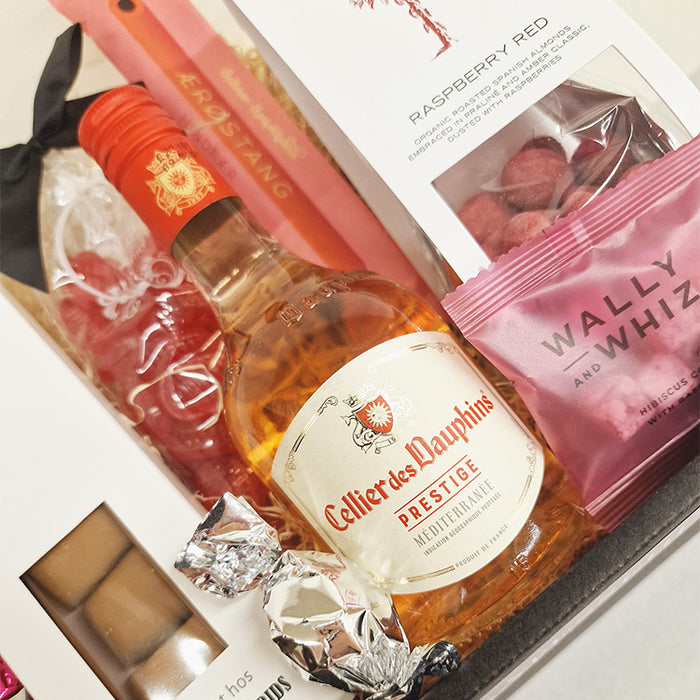 Sød feminin gavekurv med lille flaske fransk rosévin, chokolade, lakrids, mandler vingummi m.m.