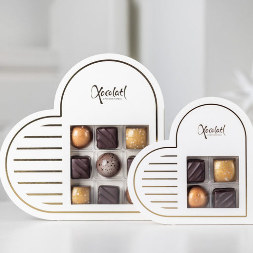 Elegant hvid hjerteformet æske med gyldne detaljer, fyldt med 9 håndlavede chokolader i smagsvarianterne nougat, marcipan, flødekaramel og saltkaramel – en perfekt lille gave til en, du holder af.