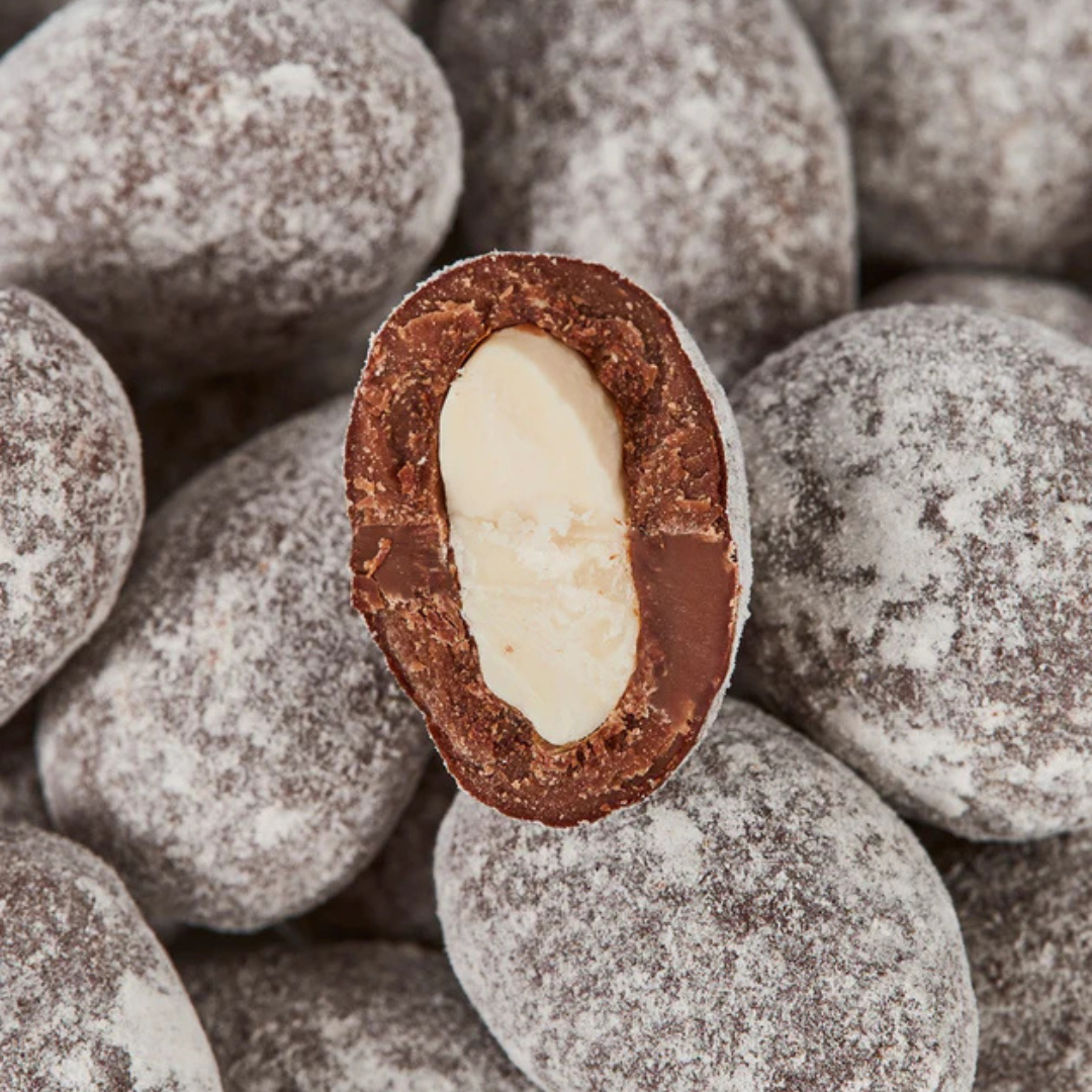 Nærbillede af en overskåret Summerbird lakridsmandel med synlig hvid mandel, chokolade og fint granulat.