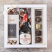 Sød og elegant gaveæske med vin, fyldte chokolader og dragerede hasselnødder