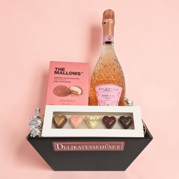 Lækker lyserød gavekurv med mousserende vin, chokolade og mallows. 