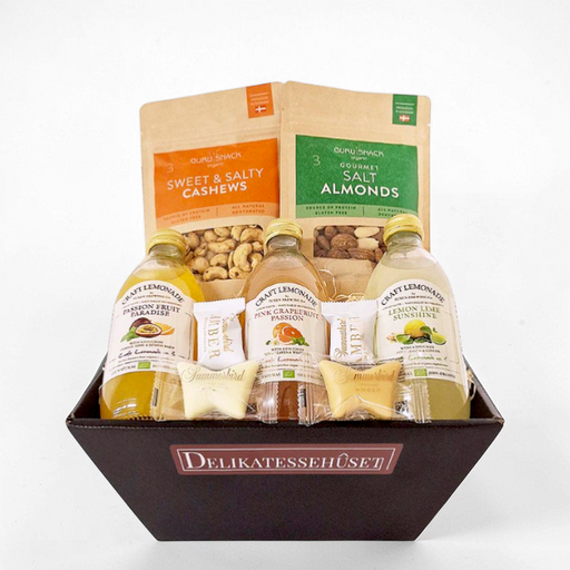 Gavekurv med økologiske varer: passionsfrugt-, grapefrugt- og citron-lime lemonade fra Tuxen Brewing, saltede mandler og cashewnødder fra Guru Snack samt chokolade fra Summerbird, pakket med træuld og cellofan
