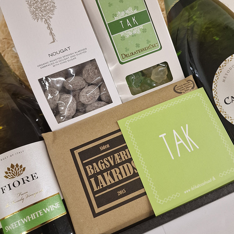 Gavekurv med hvidvin, lakrids, nougat og et grønt kort med teksten TAK.