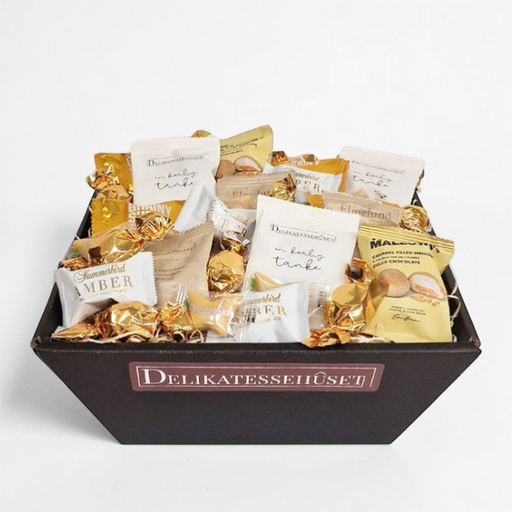 Delevenlig guld gavekurv fyldt med chokolade, lakrids, skum og chokoladekugler.
