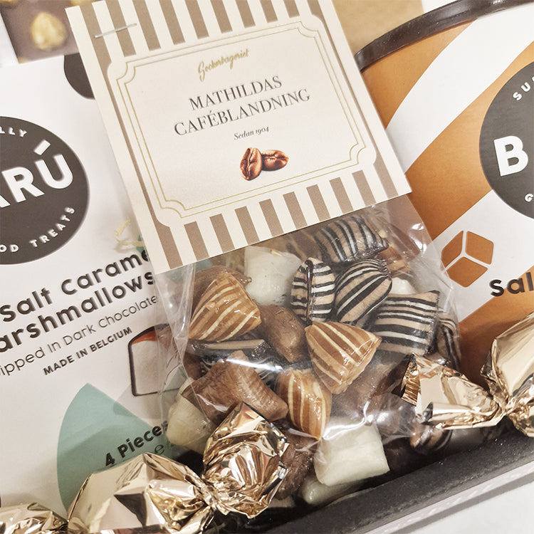 Nærbillede af god bedring gavekurv med Baru skumfiduser, chokolade, bolcher og kaffe.