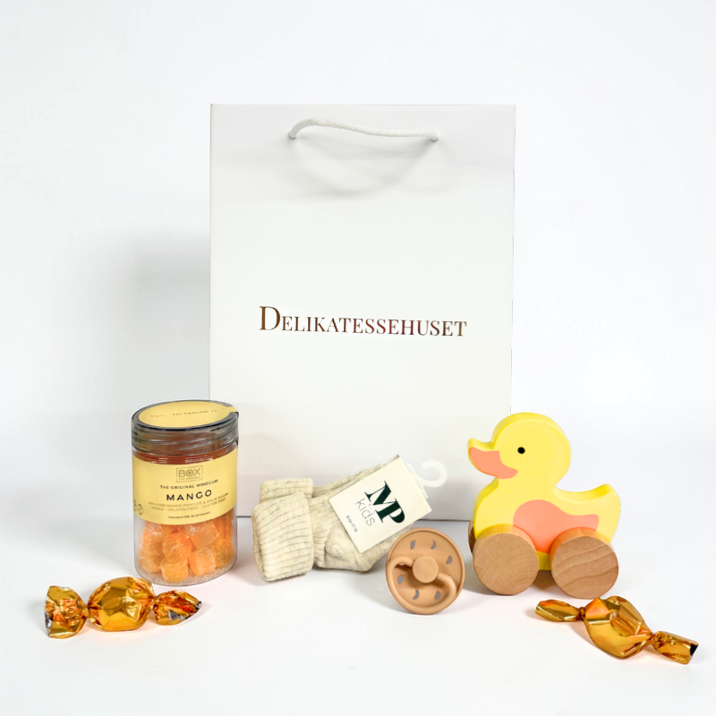 Barselsgave i gavepose med MP Danmark babystrømper, FRIGG sut str. 1, træand på hjul fra Barbo Toys, mango vingummi og 2 chokoladekugler.