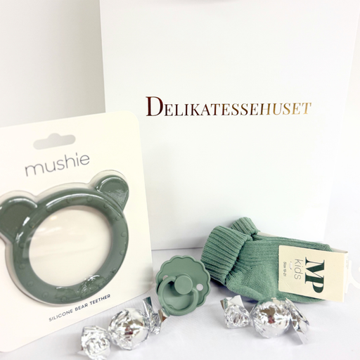 Grøn barselsgave i gavepose med strømper til baby, FRIGG sut, Mushie bidering og 2 chokoladekugler – perfekt som babyshowergave eller gave til nybagte forældre.