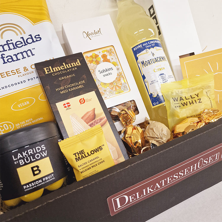 Gavekurv med gule delikatesser som lakrids, chokolade og sodavand fra Delikatessehuset.