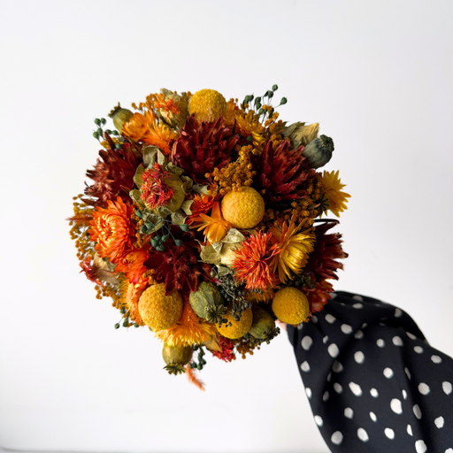 Lille tætbundet evighedsbuket med tørrede blomster i varme orange nuancer, perfekt til dekorativ bordpynt.