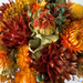Frodig mini-buket i varme orange farver, håndbundet af tørrede og præserverede blomster, der holder sig smuk i lang tid.