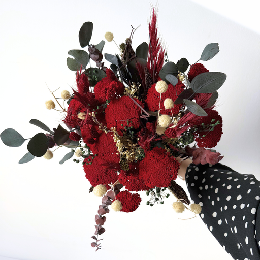 Farverig juleinspireret evighedsbuket med røde blomster og dekorative grønne og hvide elementer, perfekt til bord eller vindueskarm.