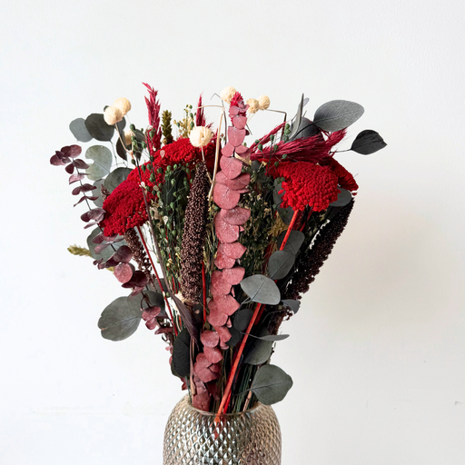 Smuk julebukket af evighedsblomster i røde nuancer med grønne og hvide detaljer, ideel til festlig juledekoration.