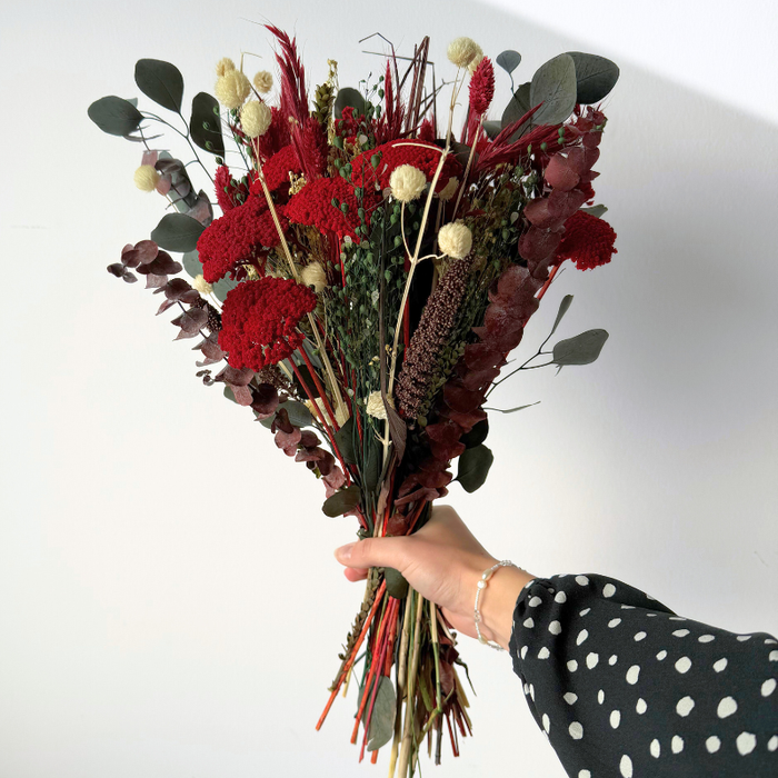Dekorativ buket til jul med tørrede røde blomster, grønne grene og hvide accenter, der bevarer skønhed hele vinteren.