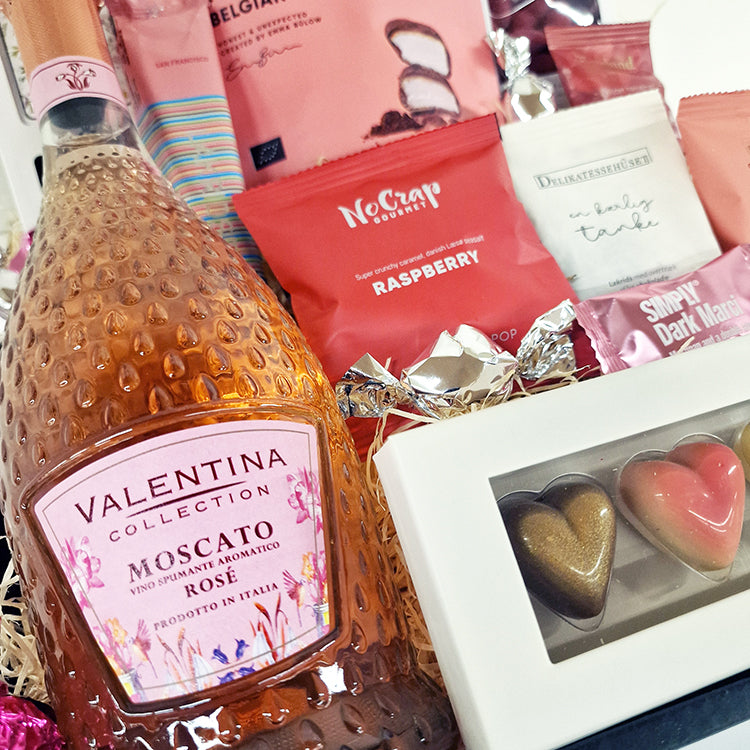 Lyserød gavekurv med Moscato Rosé, chokoladehjerter og søde sager til firmagaver.