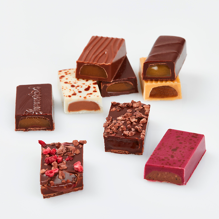 Udvalg af Summerbird tapas chokolade med marcipan, ganache og forskellige toppings på hvid baggrund.