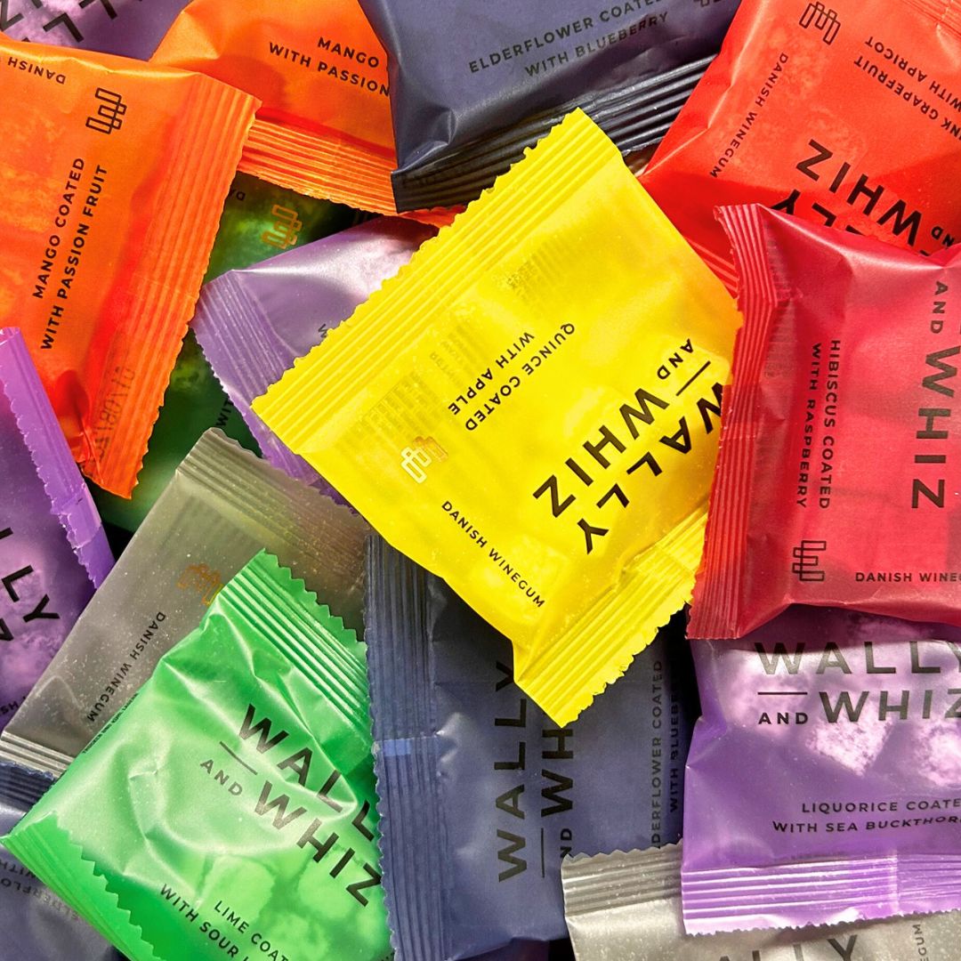 Farverige poser med Wally and Whiz gourmet-vingummier i forskellige smagsvarianter som mango, kvæde og lakrids.