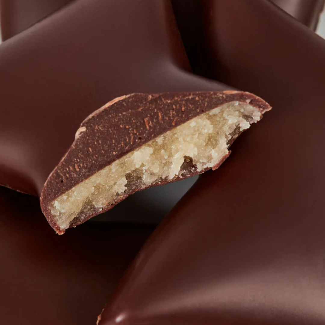 Nærbillede af overskåret fyldt chokolade med marcipanovertræk og mørk chokolade.