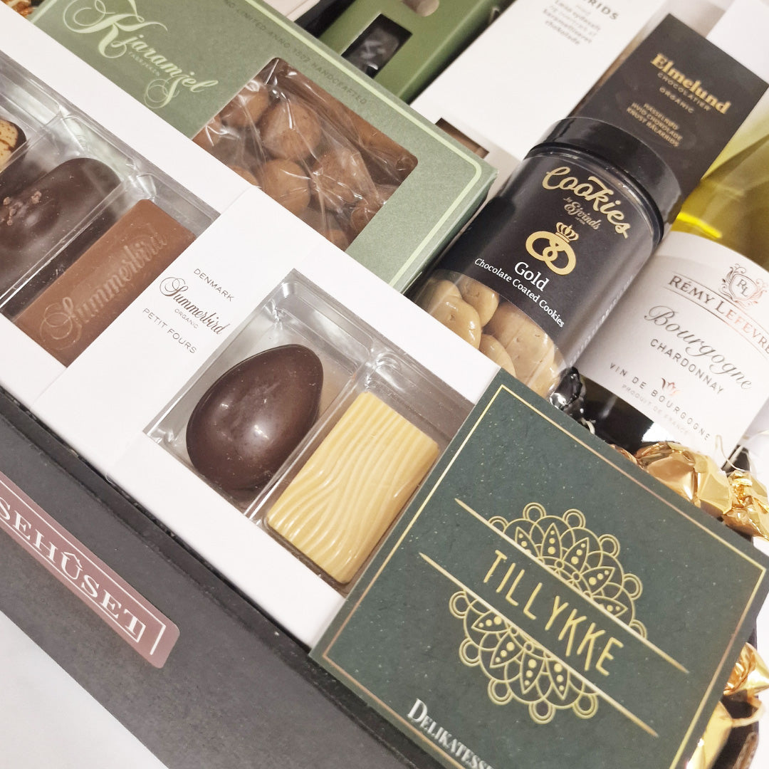 Tætpakket delikatessekasse med Summerbird chokolade, hvidvin, lakrids og tillykke kort fra Delikatessehuset.