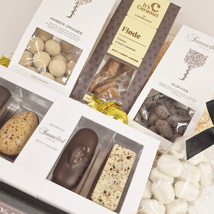 Tætpå billede af gavekurv med Summerbird chokolade, flødekarameller og bolcher til firmagaver.