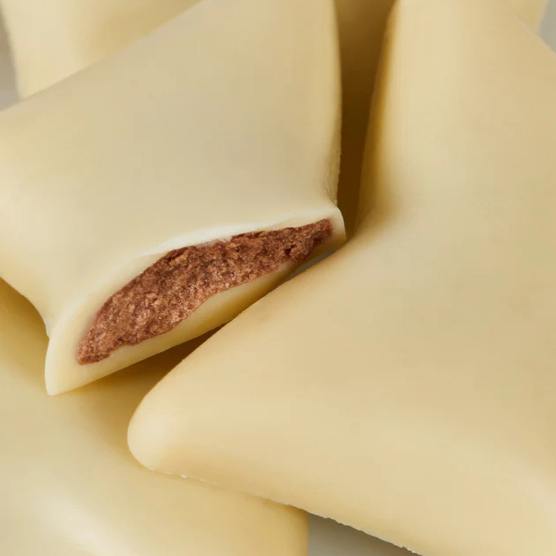 Nærbillede af trekantet fyldt chokolade med hvidt overtræk og cremet midte fra Delikatessehuset.