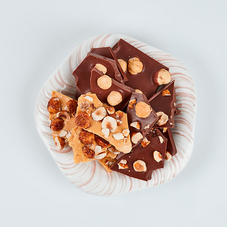 Stykker af Summerbird Amber og mørk chokolade med hele hasselnødder på en lille tallerken.